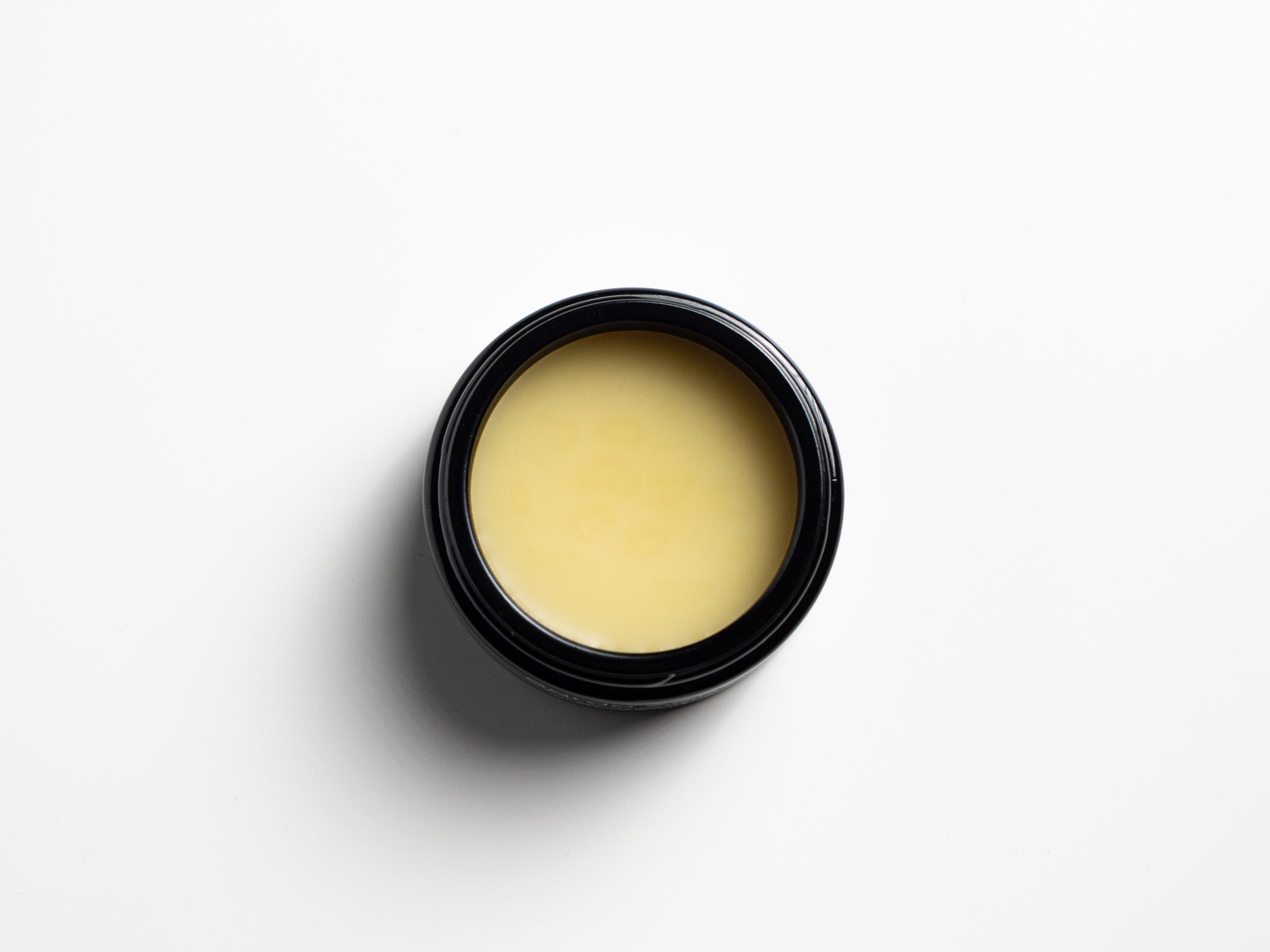 Open jar of Helichrysum Body/Face BALM with yellowish cream viewed from above