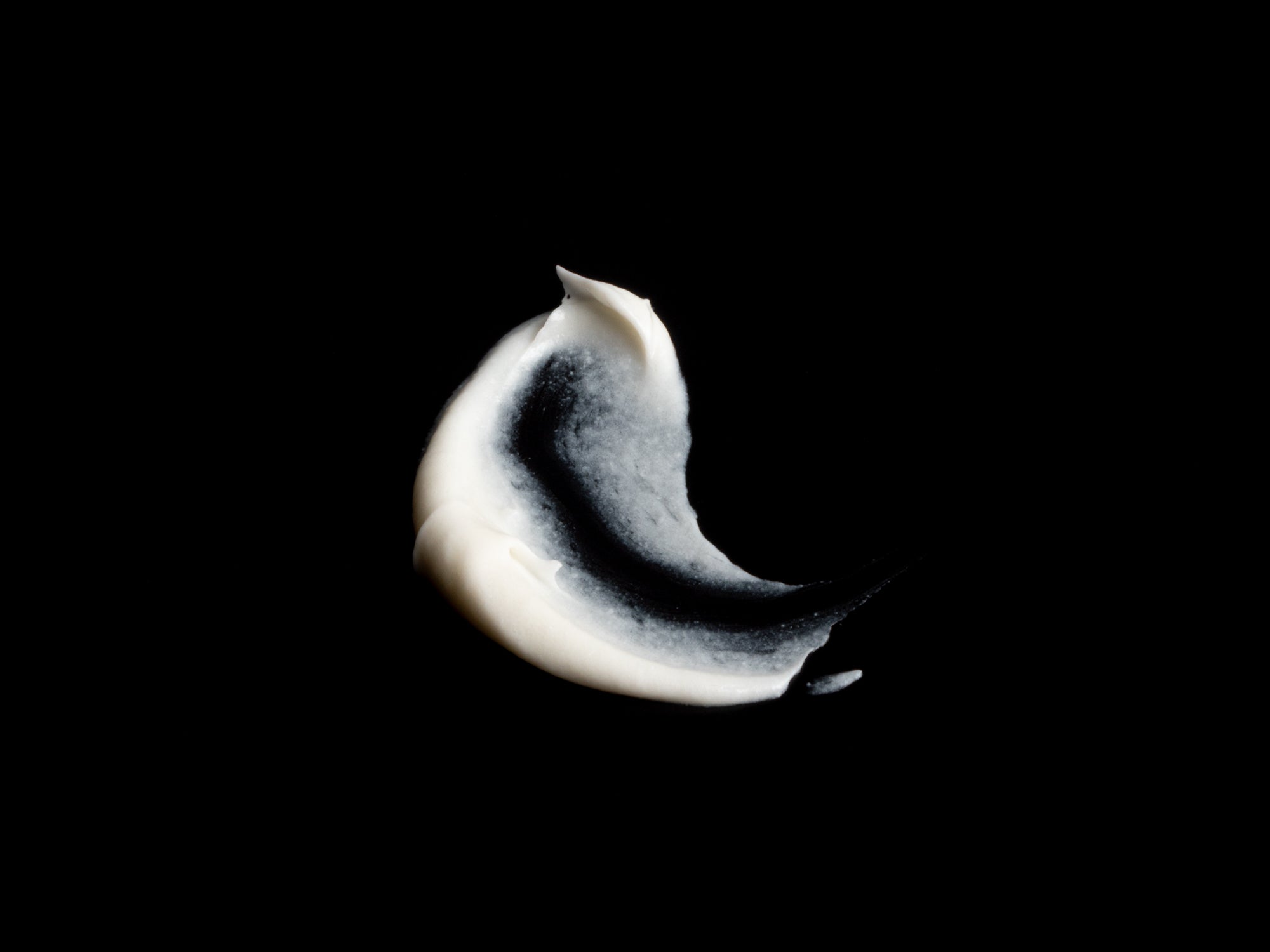 Swatch of white Helichrysum Body Cream on a black background