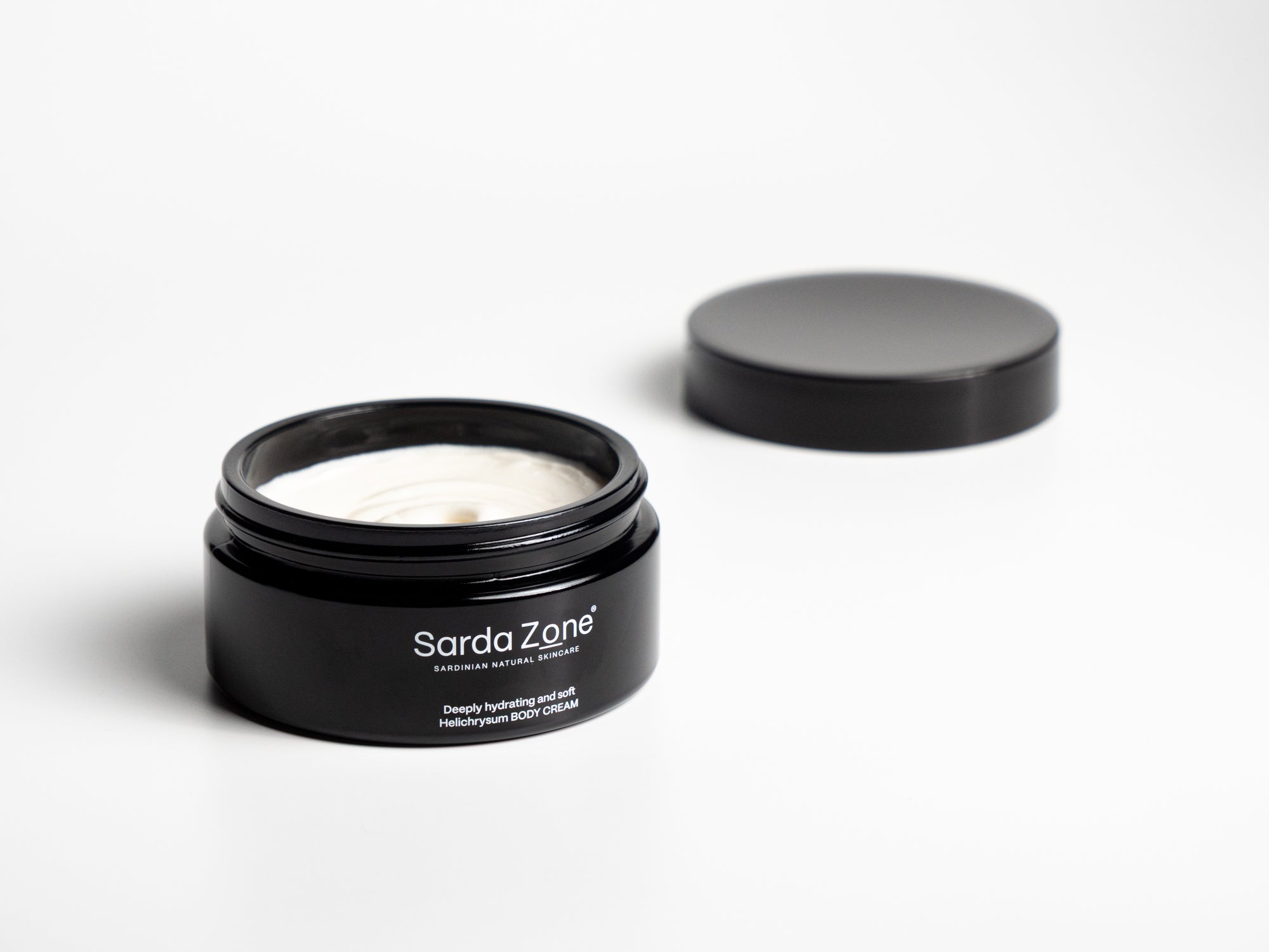 Open jar of Sarda Zone Helichrysum Body Cream with the lid beside it